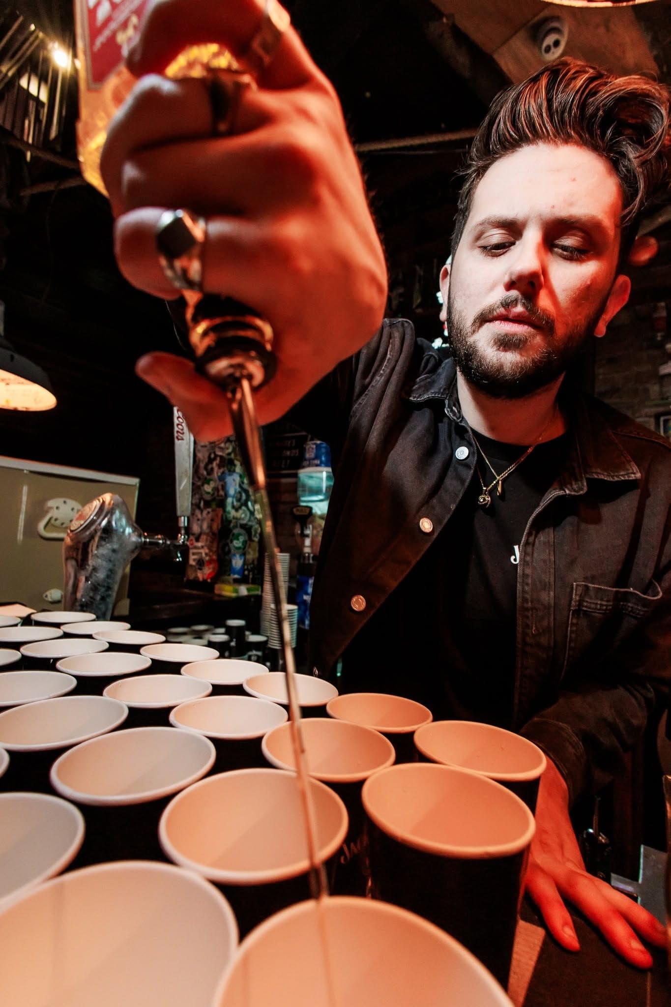Bartender pouring over a row of shot cups
